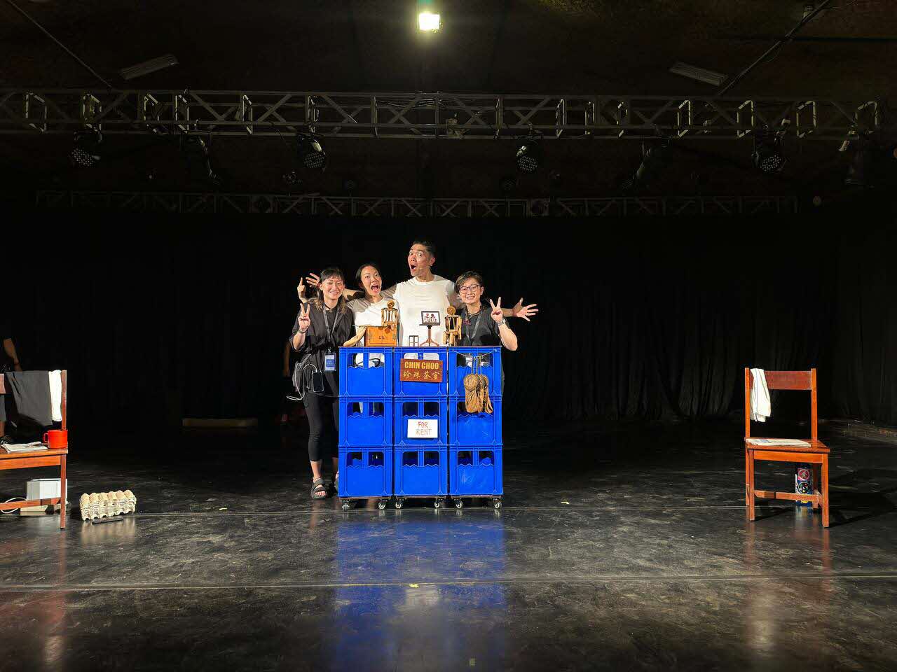 Four performers smiling and posing on stage for a group photo.